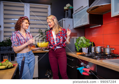 A brunette and a blonde prepare a healthy meal in the kitchen. 99097284