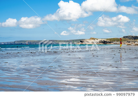 Beautiful Newquay beach with blue sea, stone cliffs and white sand in Cornwall. Red and yellow flag in the sea. South west England, selective focus Beautiful Newquay beach with blue sea, stone cliffs and white sand in Cornwall. Red and yellow flag in the sea. South west England, selective focus 99097979