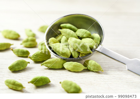 Green cardamom pods on a white wooden table, selective focus. Green cardamom pods on a white wooden table, selective focus. 99098473