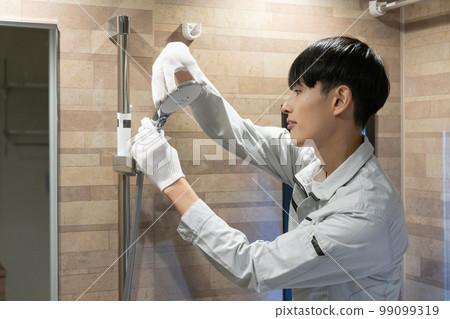 A worker inspecting the shower in the bathroom A worker inspecting the shower in the bathroom 99099319