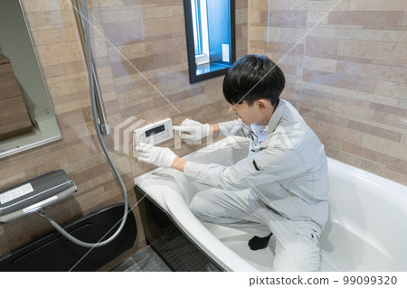 A worker inspecting the bathtub in the bathroom A worker inspecting the bathtub in the bathroom 99099320