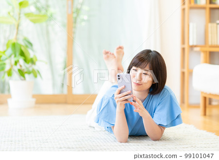 在客廳使用智能手機的年輕女性 在客廳使用智能手機的年輕女性 99101047