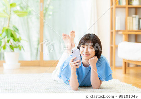 在客廳使用智能手機的年輕女性 在客廳使用智能手機的年輕女性 99101049