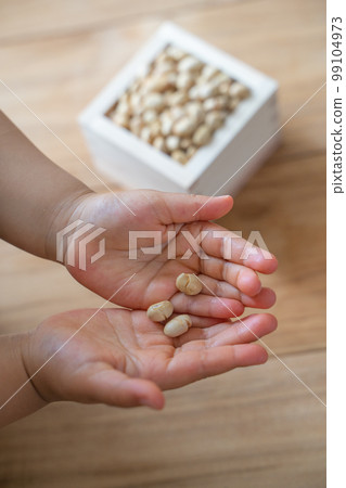 A child's hand receiving lucky beans for the number of years old 99104973