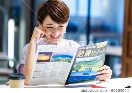 A woman looking at a travel pamphlet at a cafe Photographing cooperation: WEEK Shibadaimon (Sun Frontier Fudousan) 99105044