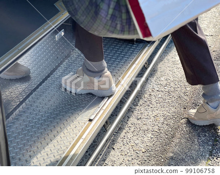 The feet of the elderly climbing the steps of the bus 99106758