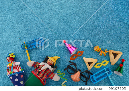 Purim celebration concept. Jewish carnival background. hamantaschen or hamans ears cookies, carnival mask and noisemaker Purim celebration concept. Jewish carnival background. hamantaschen or hamans ears cookies, carnival mask and noisemaker 99107205