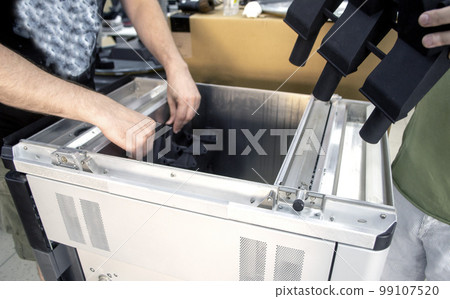 Man takes out model printed 3D printer from the workspace of a big industrial 3D printer. Model printed from polyamide powder. Two workers print an object on a powder 3D printer. Multi Jet Fusion Man takes out model printed 3D printer from the workspace of a big industrial 3D printer. Model printed from polyamide powder. Two workers print an object on a powder 3D printer. Multi Jet Fusion 99107520