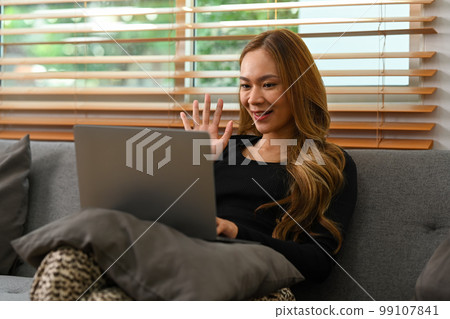 Happy woman in casual clothes having video calling, communicating online via laptop at home Happy woman in casual clothes having video calling, communicating online via laptop at home 99107841