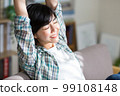 A young woman stretching on the sofa, relaxing, resting, refreshing, gymnastics 99108148