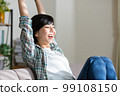 A young woman stretching on the sofa, relaxing, resting, refreshing, gymnastics 99108150