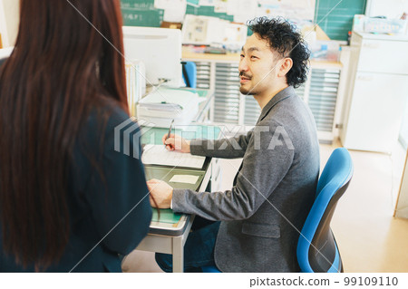 A teacher receiving student consultation in the staff room A teacher receiving student consultation in the staff room 99109110