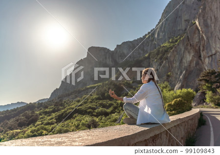Profile of a woman doing yoga in the top of a cliff in the mount 99109843