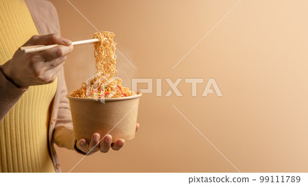 Woman Using Chopsticks to Eating Hot Boiled Instant Cup Noodles. Cheap Asian Fast food Concepts. Side View Woman Using Chopsticks to Eating Hot Boiled Instant Cup Noodles. Cheap Asian Fast food Concepts. Side View 99111789