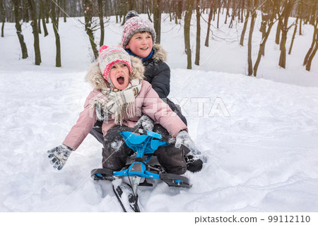 Children in winter outdoors ride a snow scooter Children in winter outdoors ride a snow scooter 99112110