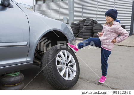 Little girl at a car service. Replacing wheels on a car. Repair service 99112258