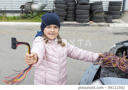 A child mechanic changes fuses in a car. Repair services in car service 99112302