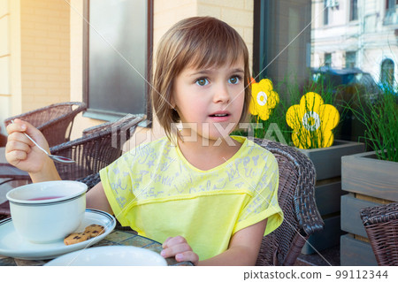 Girl drinking tea in a cafe on a summer terrace 99112344