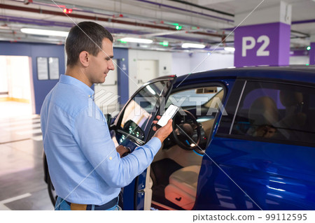 A businessman with a phone in a his hand in an underground parking lot 99112595