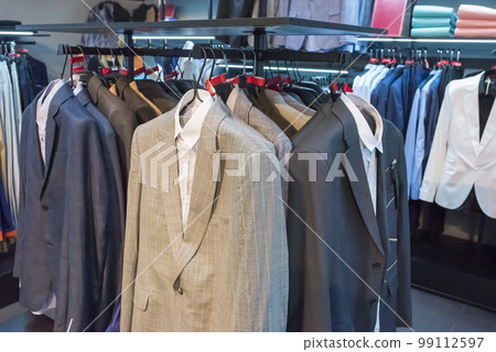 Clothes on hangers in a store. Rack with clothes in a shopping center, suits, jackets 99112597