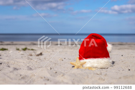 Santa Claus hat and starfish on the sandy beach Santa Claus hat and starfish on the sandy beach 99112688