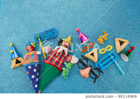 Purim celebration concept. Jewish carnival background. hamantaschen or hamans ears cookies, carnival mask and noisemaker Purim celebration concept. Jewish carnival background. hamantaschen or hamans ears cookies, carnival mask and noisemaker 99114969