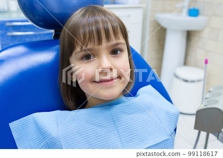 A portrait of a child patient in a dental chair in a dentists office 99118617