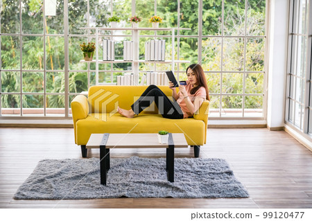 Young Asian girl using credit card to make online payment on tablet 99120477