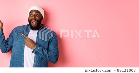 Amazed Black guy showing awesome promo offer, smiling and pointing fingers at upper left corner banner, pink background Amazed Black guy showing awesome promo offer, smiling and pointing fingers at upper left corner banner, pink background 99121008