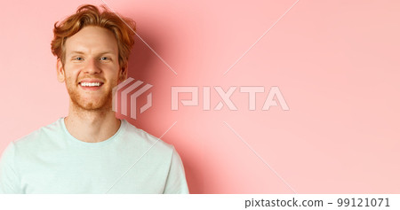 Happy young man with beard and messsy red haircut, smiling with white teeth and cheerful expression, standing over pink background 99121071