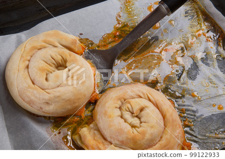 The cook removes the golden hot vertuta from the baking sheet with a spatula, close-up The cook removes the golden hot vertuta from the baking sheet with a spatula, close-up 99122933