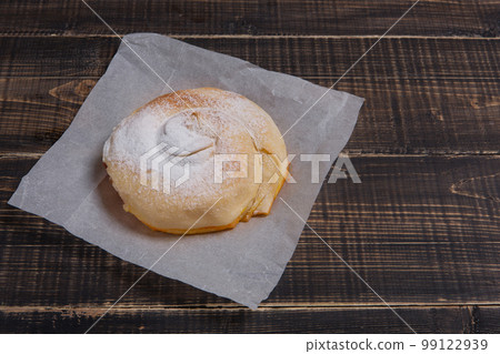 Ready vertuta with pumpkin lies on parchment paper, sprinkled with powdered sugar, on a wooden table, side view 99122939