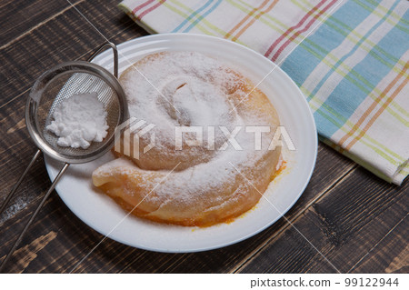 Ready-made vertuta with pumpkin lies on a plate, sprinkled with powdered sugar, a towel is nearby Ready-made vertuta with pumpkin lies on a plate, sprinkled with powdered sugar, a towel is nearby 99122944