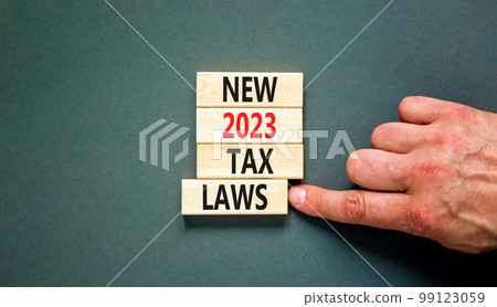 New 2023 tax laws symbol. Concept words New 2023 tax laws on wooden blocks. Beautiful grey table grey background. Businessman hand. Business new 2023 tax laws concept. Copy space. 99123059