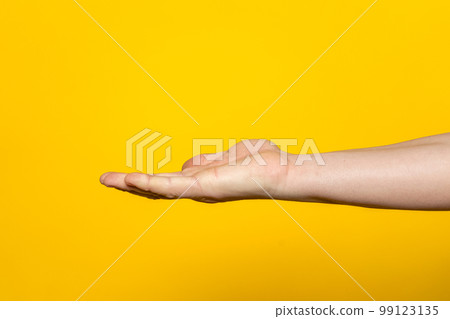 Strong hand of man with palm up presenting an imaginary product in advertising concept isolated on yellow background. Strong hand of man with palm up presenting an imaginary product in advertising concept isolated on yellow background. 99123135
