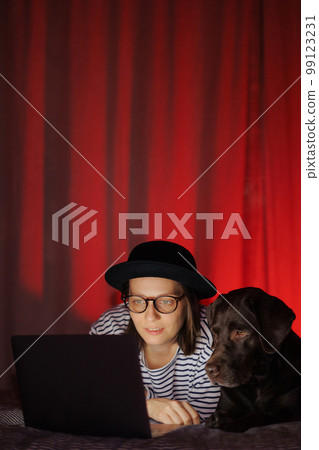 woman watches movie with glasses with, Labrador retriever dog, eats popcorn woman watches movie with glasses with, Labrador retriever dog, eats popcorn 99123231