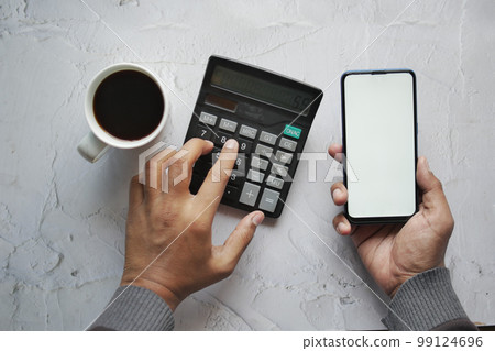 men using smart phone and calculator on table men using smart phone and calculator on table 99124696