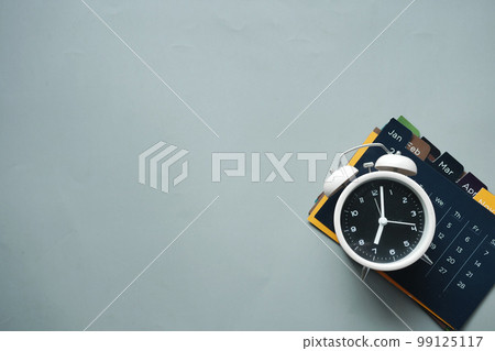old alarm clock and a calendar on gray background old alarm clock and a calendar on gray background 99125117