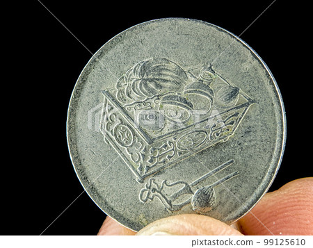 Closeup finger holding old 20 cent Malaysia coin on a black background. Closeup finger holding old 20 cent Malaysia coin on a black background. 99125610