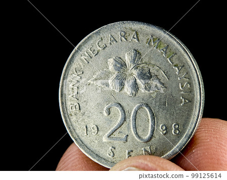 Closeup finger holding old 20 cent Malaysia coin on a black background. Closeup finger holding old 20 cent Malaysia coin on a black background. 99125614