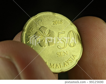 Closeup finger holding 50 cent Malaysia coin on a black background. Closeup finger holding 50 cent Malaysia coin on a black background. 99125690