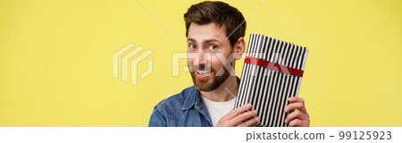 Handsome smiling man shaking gift box and looking at camera. Great present Handsome smiling man shaking gift box and looking at camera. Great present 99125923