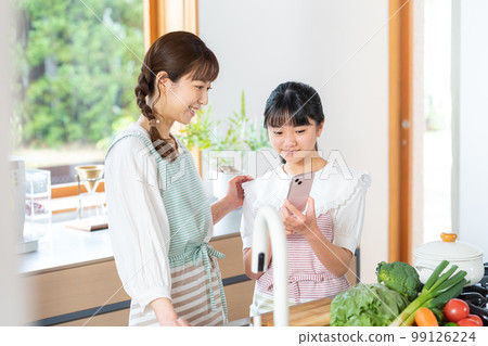 Parents and children operating a smartphone in the kitchen Parents and children operating a smartphone in the kitchen 99126224