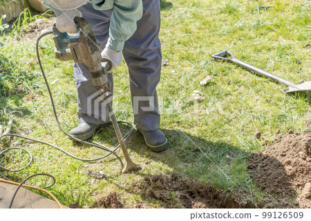 A civil engineer for waterworks digging the ground with an electric hammer A civil engineer for waterworks digging the ground with an electric hammer 99126509