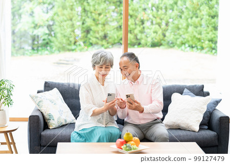 Senior couple with smartphones in the living room 99127479