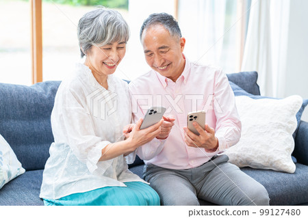 在客廳裡拿著智能手機的老年夫婦 99127480