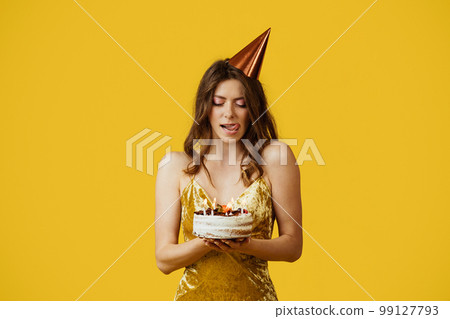 Pretty woman in dress licking her lips from temptation, looking at delicious birthday cake against yellow background 99127793