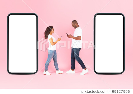 Modern online communication. Full length of black couple walking near two huge smartphones with empty screens, mockup 99127906