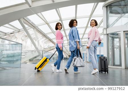 Three Beautiful Women Walking With Luggage At Airport And Turning At Camera 99127912