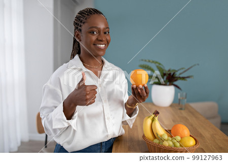 Happy young black woman nutritionist showing fresh orange 99127963